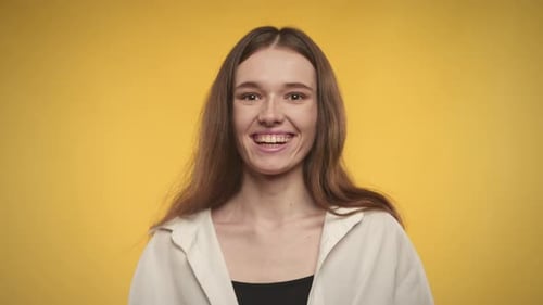 Smiling Young Woman Laughing Against Yellow Backdrop