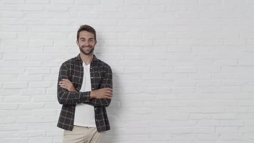 Man Poses in Front of White Brick Wall