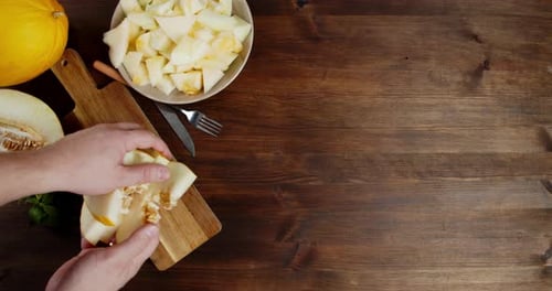 Un
mâle met à la main des tranches de melon sur une planche à découper.