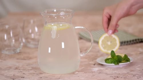 Adding Lemon and Mint to Glass Pitcher of Water