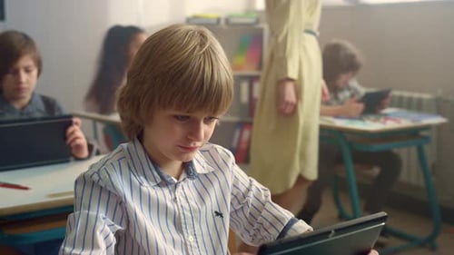 Boy Looking on Screen of Digital Tablet During Lesson