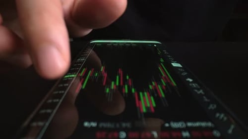 Businessman reading stock market chart on mobile phone, trading online.