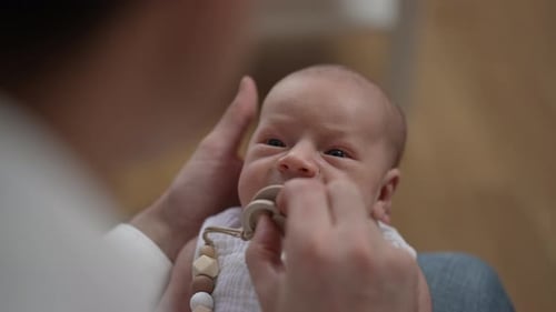 Nahaufnahme Porträt von Curios Niedliches Neugeborenes Baby in den Händen eines liebenden Mannes drinnen zu Hause