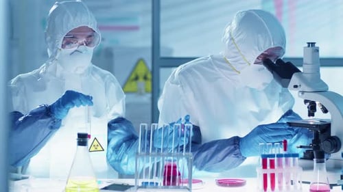 Two Scientists in Protective Suits Working Together in Laboratory