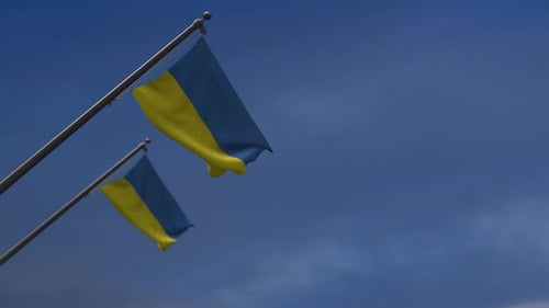Waving Ukrainian Flag on a Pole Against Blue Sky