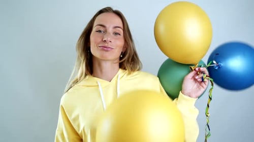 Woman Smiling with Colorful Balloons in an Indoor Setting