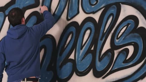 Jovem pintor urbano desenhando grafite na parede