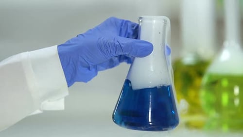 Gloved Hand Holding Flask with Emitting Vapor