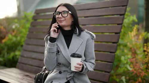 Smiling Woman Talking on Phone While Seated on Bench