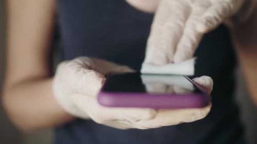 Adult Woman Disinfecting Mobile Phone with Wipe and Gloves
