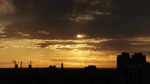 sunset sky against the background of pipes of an industrial plant and residential buildings of the c