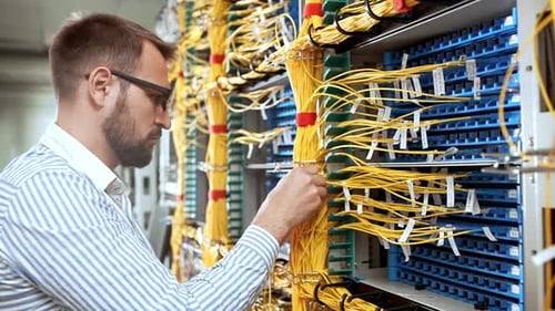 IT Technician Working on Server Cables in Data Center