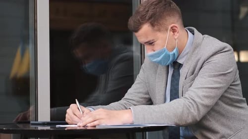 Business Man Wearing Face Mask Working with Papers in Cafe