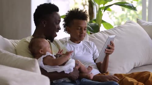 Father, Son, and Baby Relaxing with Tablet