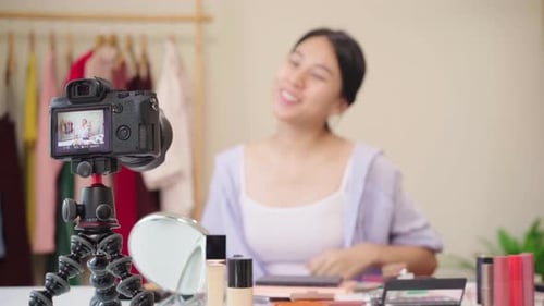 La bloguera de belleza presenta cosméticos de belleza sentada frente a la cámara frontal para grabar un vídeo de una mujer asiática.