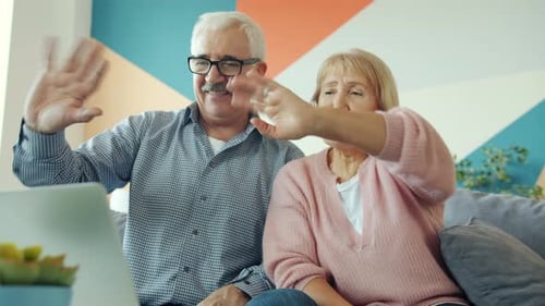 Senior Couple Waving During Laptop Video Call