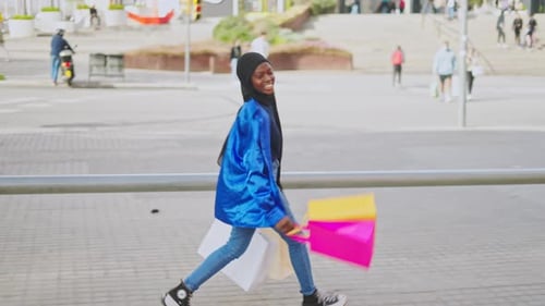 Young Woman Walking with Shopping Bags in City