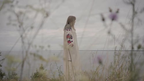 Carefree Caucasian Woman Wearing Long Summer Fashion Dress Standing on the Field on the Background