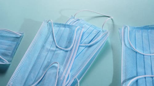 Unused Blue Surgical Masks on Light Blue Surface