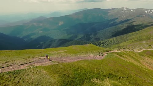 Two Hikers Standing on Top of a Mountain with Large Backpacks