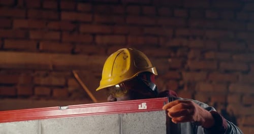 Black Contractor Measuring Brick Wall