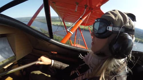 Woman flying vintage biplane over landscape