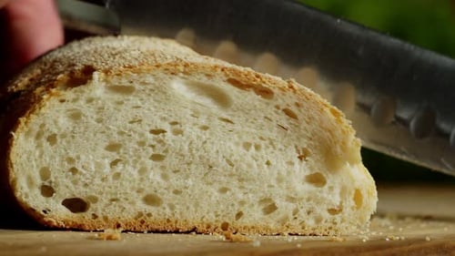 Closeup of Hand with Kitchen Knife Slicing Crispbread Indoors