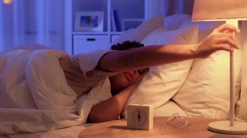 Woman in Bed Turns Off Lamp and Alarm