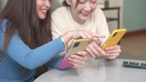 Two Women Using Phones Indoors Together