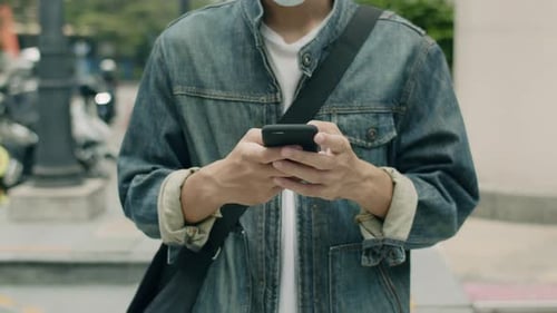 Young Adult Uses Cell Phone on Urban Street