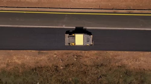 Road roller pressing fresh put Asphalt on a new road, Aerial follow footage.