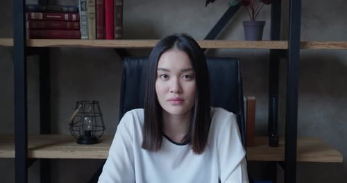 Smiling Woman Sitting in front of Bookshelf