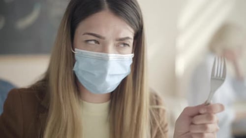 Woman Wearing Mask Sprays Sanitizer on Fork