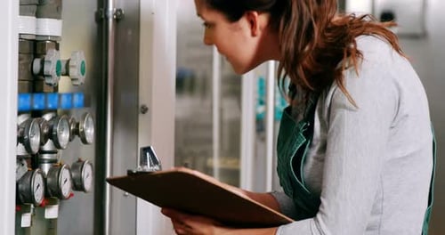 Worker maintaining record on clipboard in factory
