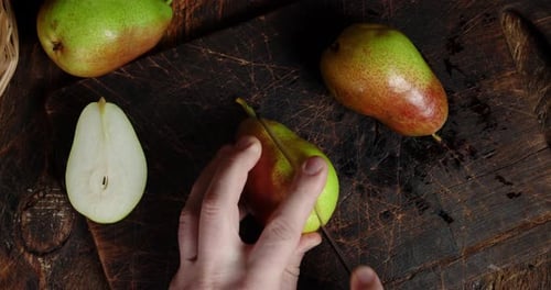 Male Hand Cut Fresh Pears Into Two Halves.