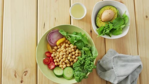 Video of bowls of fresh salad with green leaves on wooden background