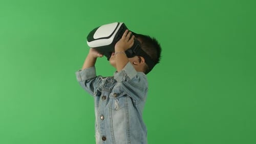 Young Boy Wearing VR Headset Against Green Screen