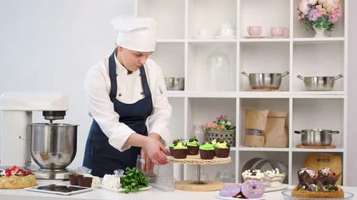 Woman Chef Decorating Cupcakes in Kitchen