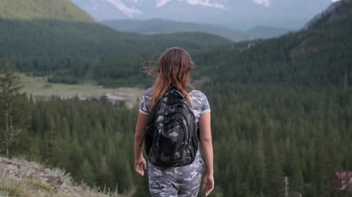 Happy Girl Tourist at the Peak of the Mountain Raises Her Hands Up and Is Proud of Her Success
