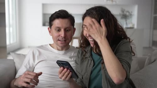 Excited Couple Receives Good News on Phone at Home