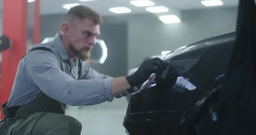 Técnico barbudo aplicando película en el faro