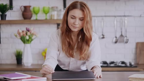 Woman Opens Laptop and Smiles in Kitchen
