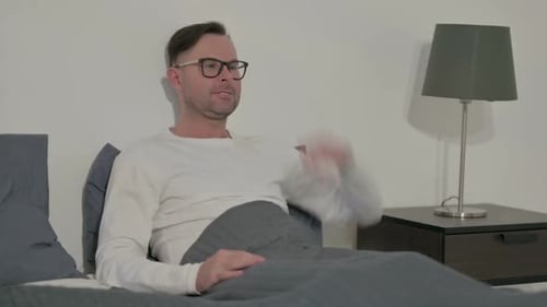 Man Sitting up in Bed at Home