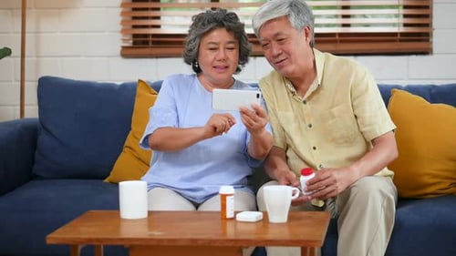 Elderly Couple Using Mobile Phone on Couch