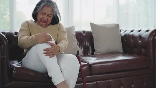 Senior Woman Massaging Knee with Painful Expression