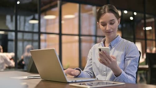 Woman Working on Laptop and Using Phone