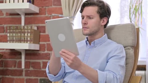 Excited Man Using Tablet Indoors