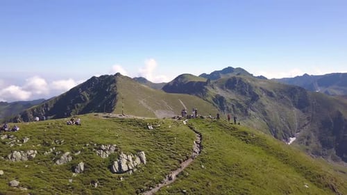 Aerial view of hikers standing on summit of mountain looking out on amazing and dramatic landscape a