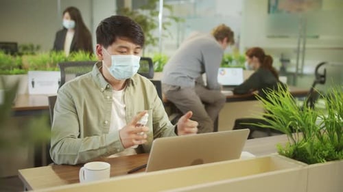 Adult Using Hand Sanitizer in Modern Office