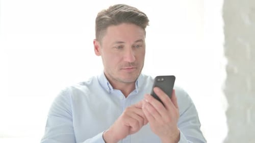 Man Using Smartphone Indoors During Daytime